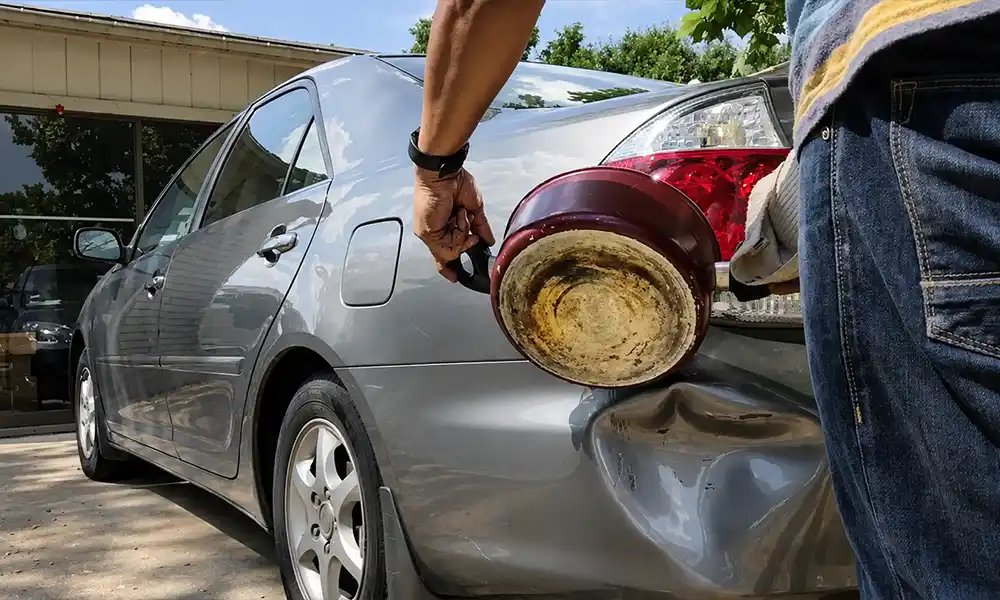 Hot water being poured on plastic bumper dent for DIY removal